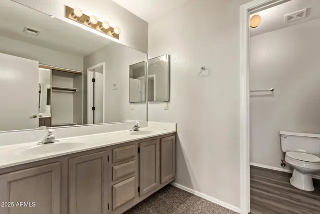 a spacious bathroom with a granite countertop sink a toilet and a mirror