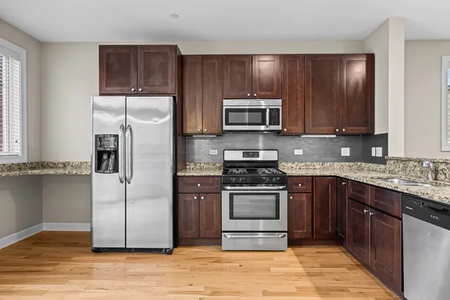 a kitchen with granite countertop wooden cabinets stainless steel appliances and a window