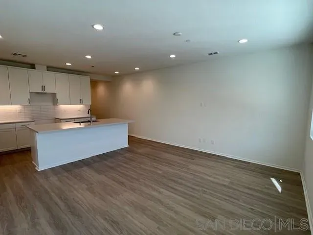 a view of kitchen with kitchen island wooden floor center island and stainless steel appliances