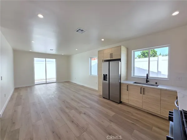 a large kitchen with a dishwasher a refrigerator a sink dishwasher with wooden floor and cabinets