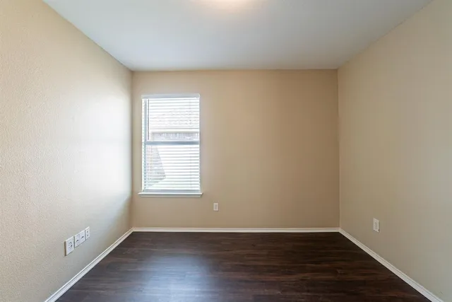 an empty room with wooden floor and window