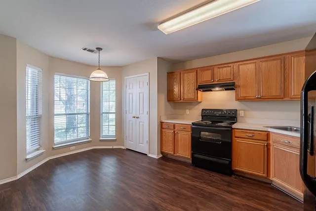 a kitchen with stainless steel appliances granite countertop a stove a refrigerator and a sink with wooden cabinets