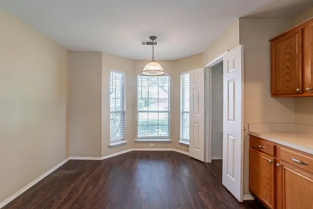 an empty room with wooden floor chandelier and windows