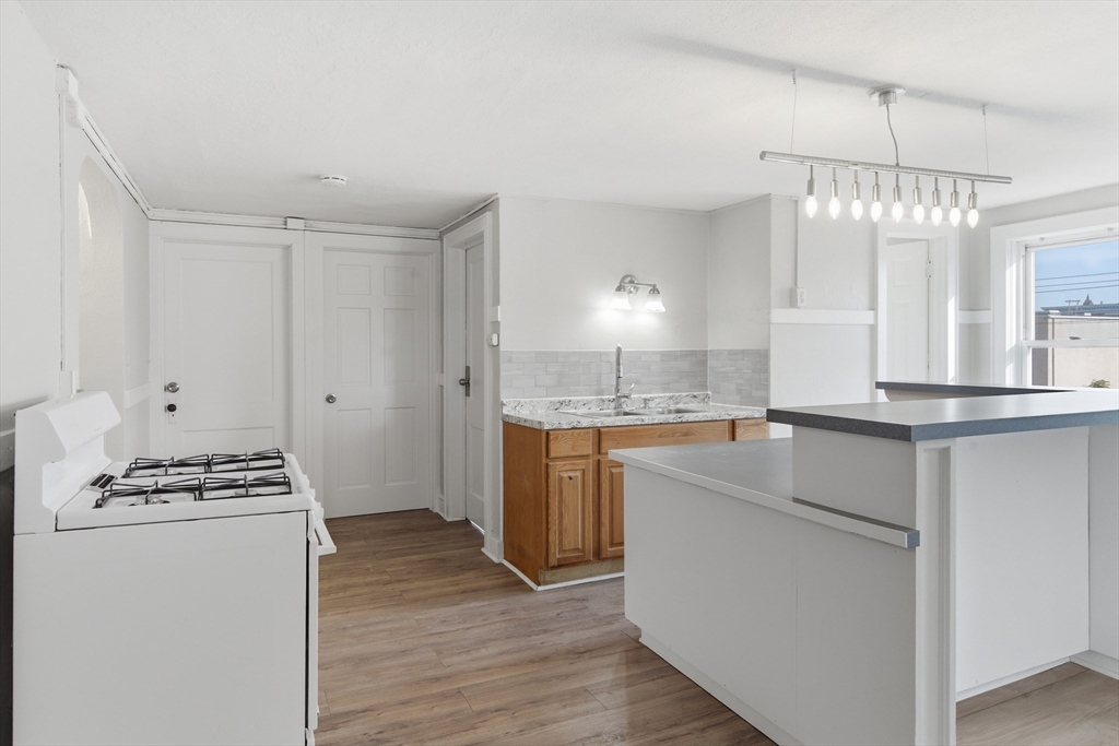293 Clemente Street, Unit 3R Holyoke, MA 01040 - Photo 2 of 14 a kitchen with kitchen island white cabinets and white appliances
