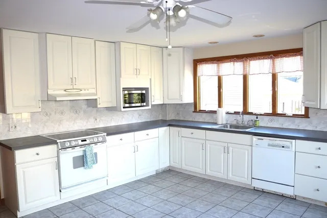 a kitchen with granite countertop white cabinets white appliances with a sink and dishwasher