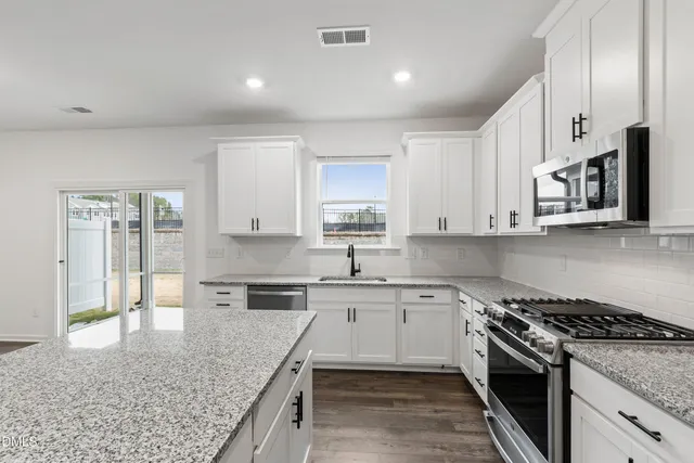 a kitchen with stainless steel appliances granite countertop a stove a sink and a microwave