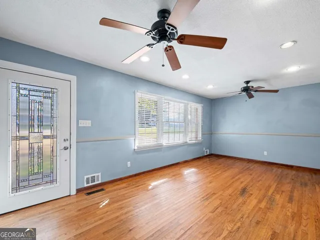 a view of an empty room with a window and wooden floor