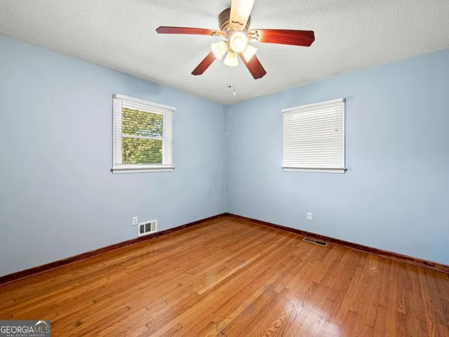 a view of an empty room with window and wooden floor
