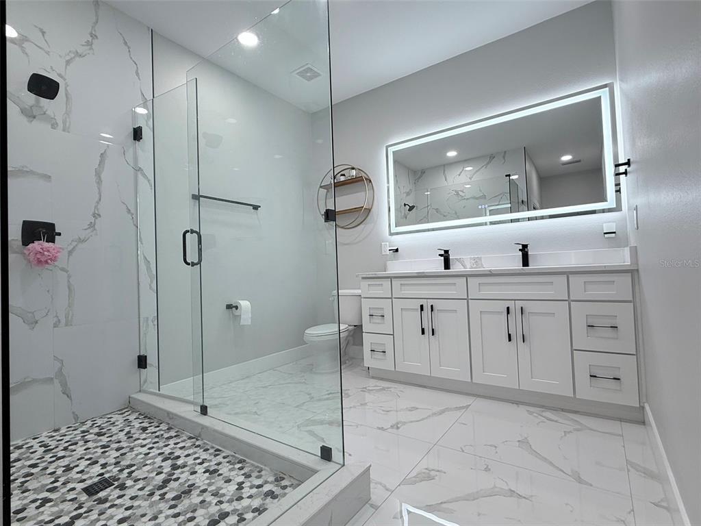 7403 Edgemere Road Tampa, FL 33625 - Photo 22 of 41 a bathroom with a granite countertop sink mirror and shower