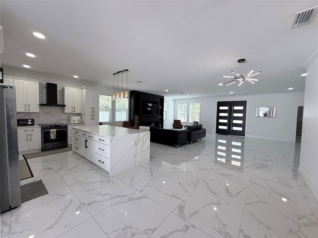 7403 Edgemere Road Tampa, FL 33625 - Photo 6 of 41 a large white kitchen with kitchen island a stove a sink a microwave and a refrigerator