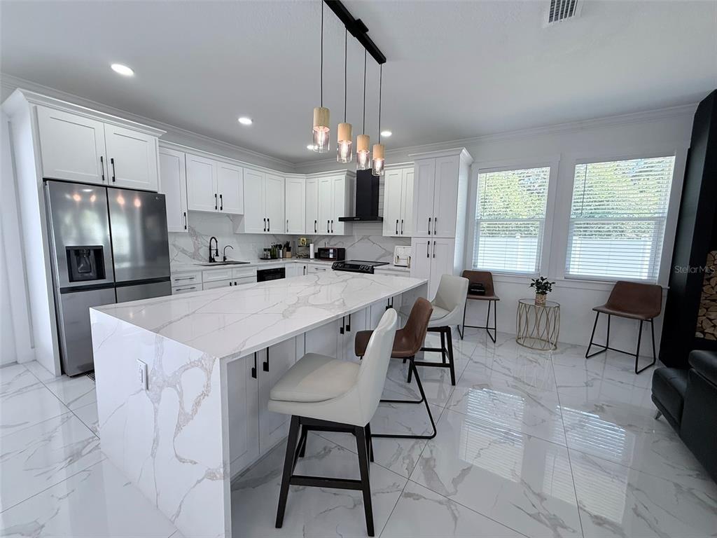 7403 Edgemere Road Tampa, FL 33625 - Photo 8 of 41 a kitchen with kitchen island a dining table chairs stainless steel appliances and cabinets