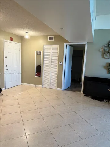 a view of an empty room with kitchen and window