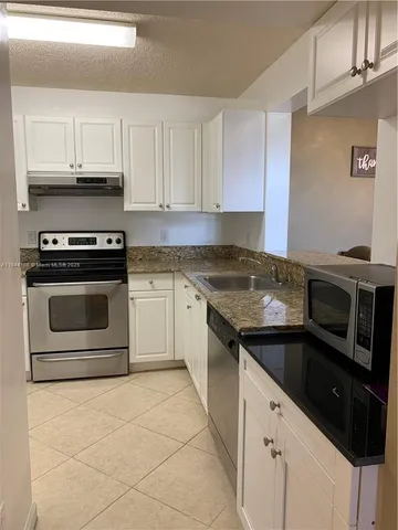 a kitchen with granite countertop a stove sink and cabinets