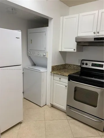 a kitchen with granite countertop white cabinets and white appliances