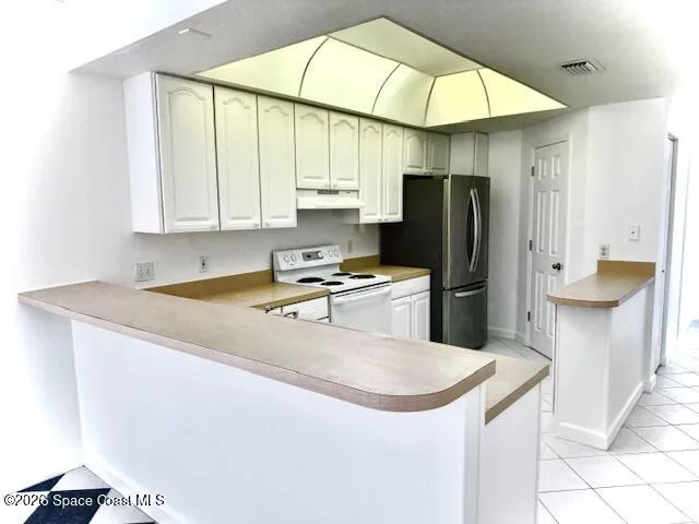 a kitchen with stainless steel appliances granite countertop a sink a stove a refrigerator a washer dryer and white cabinets