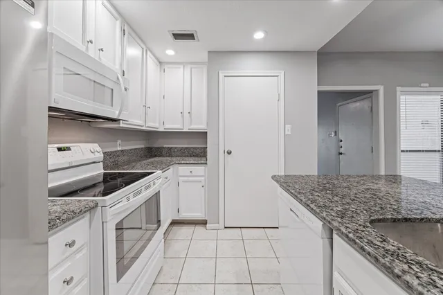 a kitchen with granite countertop white cabinets and white appliances