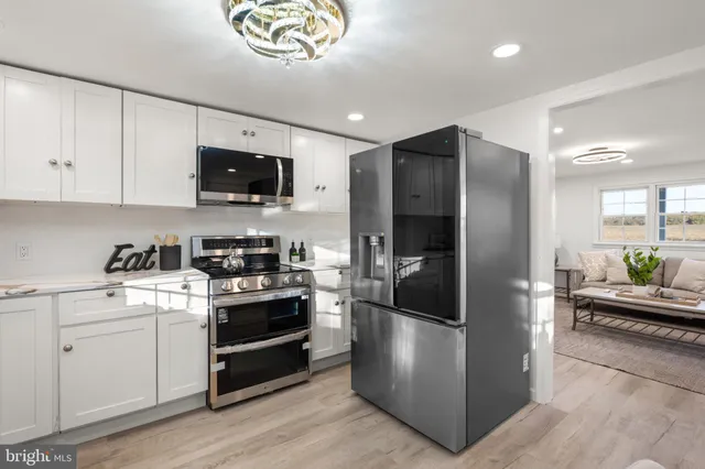 a kitchen with stainless steel appliances granite countertop a refrigerator a stove a sink and a microwave