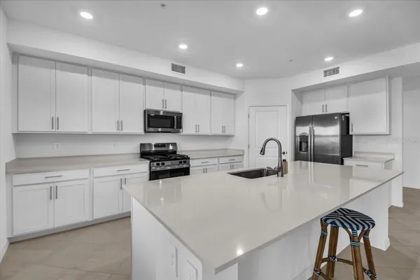 a kitchen with stainless steel appliances granite countertop white cabinets a sink a stove a microwave and a refrigerator
