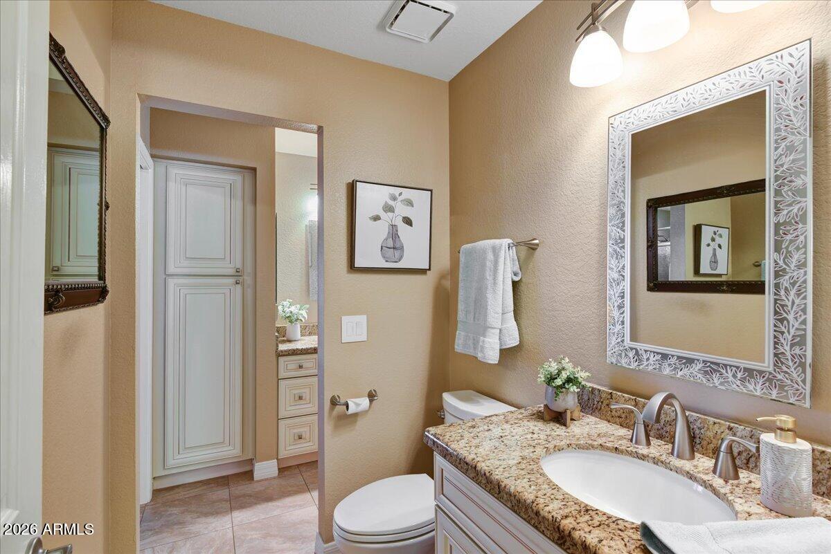9136 West Rimrock Drive Peoria, AZ 85382 - Photo 18 of 25 a bathroom with a granite countertop sink toilet a mirror and shower