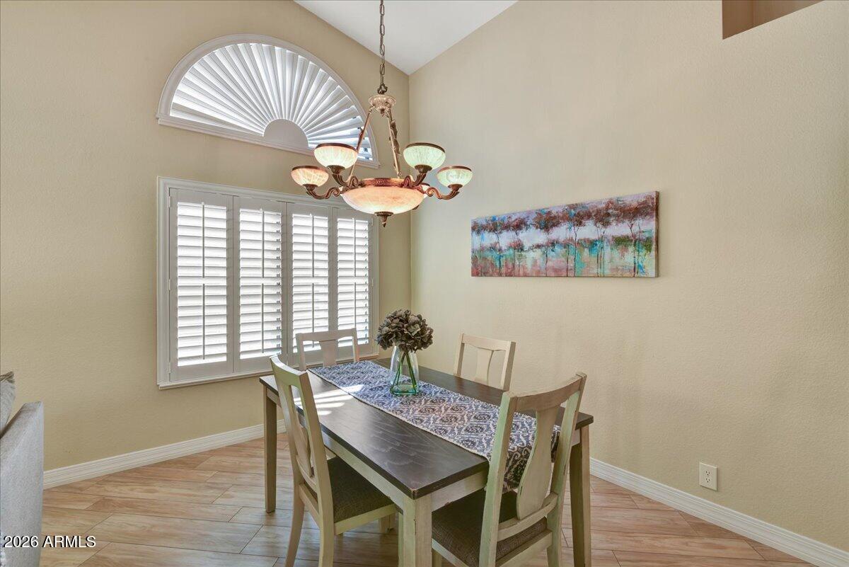 9136 West Rimrock Drive Peoria, AZ 85382 - Photo 5 of 25 a dining room with wooden floor a chandelier a wooden table and chairs