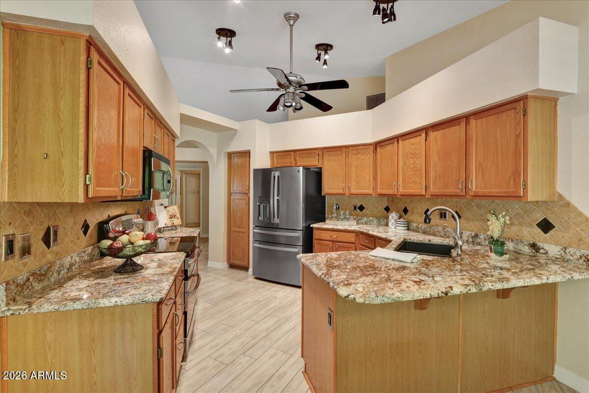 9136 West Rimrock Drive Peoria, AZ 85382 - Photo 8 of 25 a kitchen with sink a refrigerator and wooden cabinets