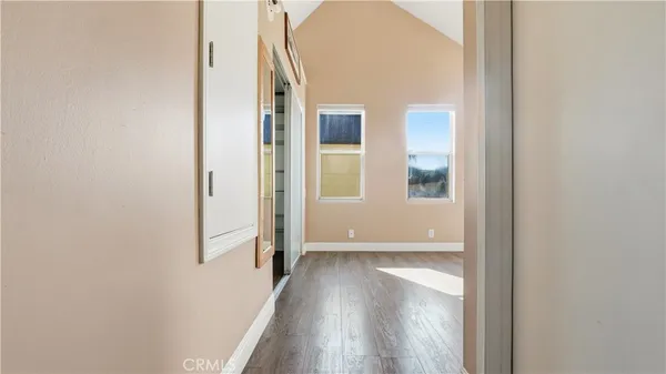 a view of a hallway with wooden floor and a bathroom