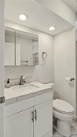 a bathroom with a granite countertop sink toilet and mirror