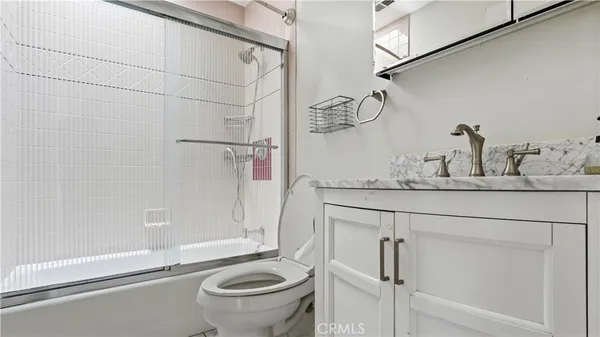 a bathroom with a granite countertop sink a toilet and shower