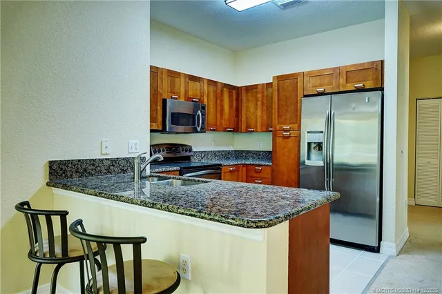 a kitchen with stainless steel appliances granite countertop a sink a microwave a refrigerator and a stove