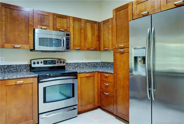 a kitchen with stainless steel appliances granite countertop a refrigerator and a stove top oven