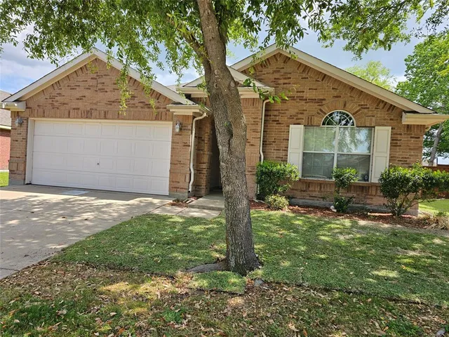 a backyard of a house with table and chairs plants and large tree