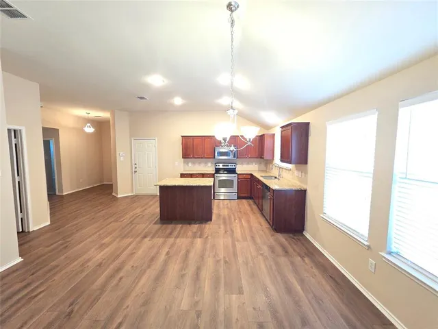 a kitchen with stainless steel appliances kitchen island wooden floors and sink