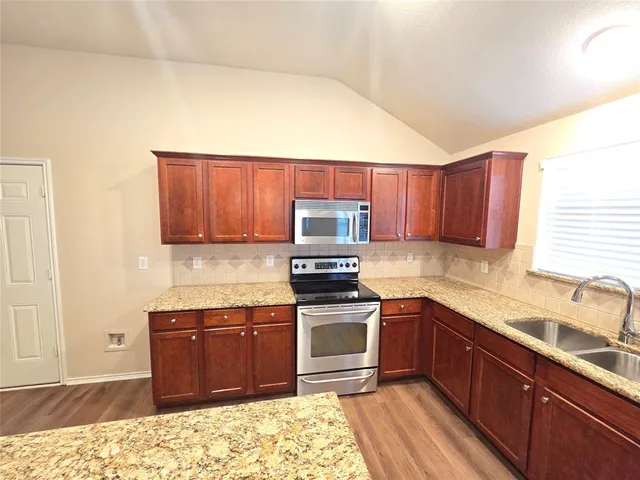 a large kitchen with kitchen island a large counter top space a sink stainless steel appliances and cabinets