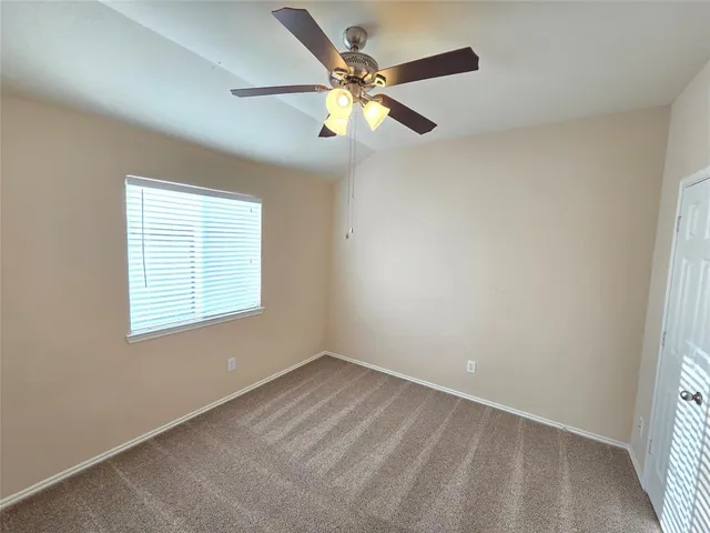 an empty room with a window and a fan