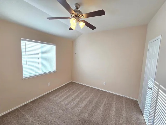 an empty room with a window and a fan