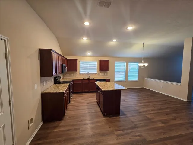 a open kitchen with stainless steel appliances granite countertop a refrigerator a sink dishwasher and a oven with wooden floor