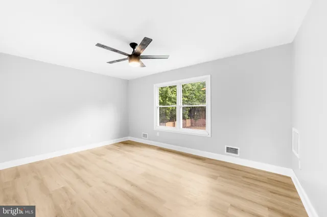 an empty room with a window and a ceiling fan