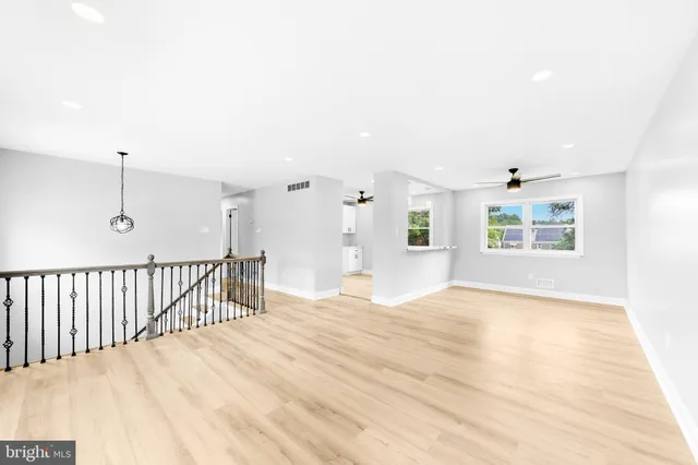 a view of an empty room with window and wooden floor