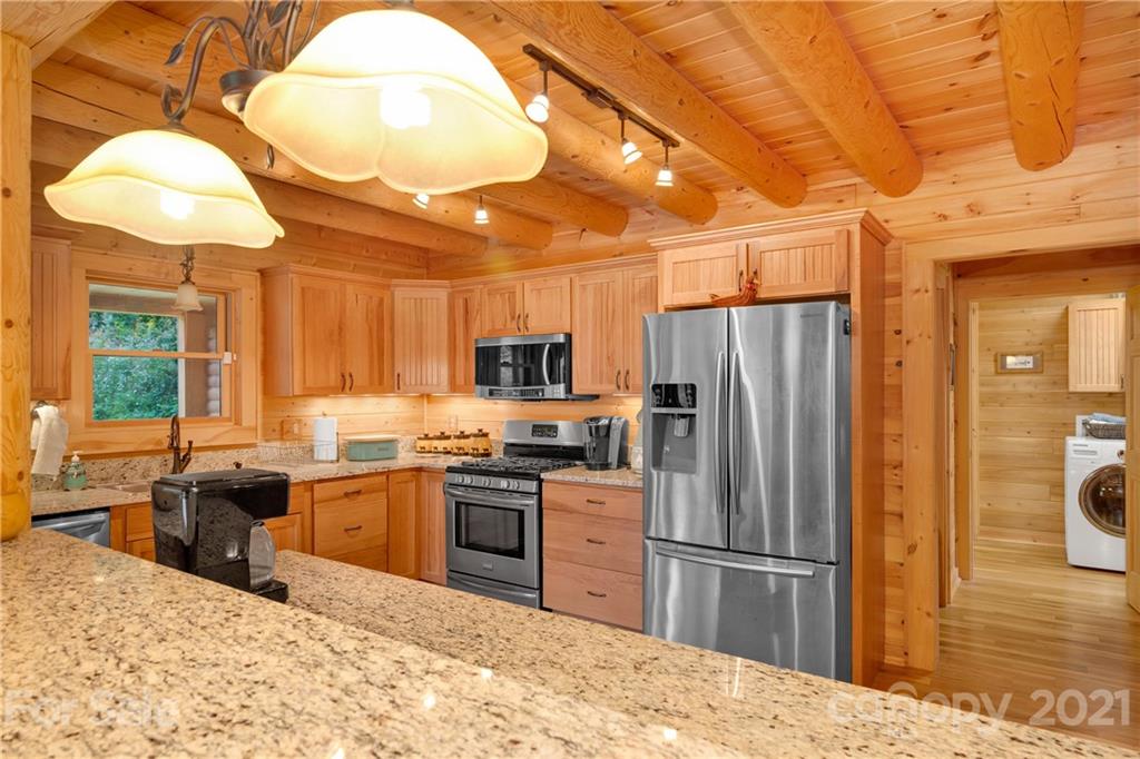 210 Angel Falls Road Clyde, NC 28721 - Photo 16 of 40 a kitchen with stainless steel appliances kitchen island granite countertop a refrigerator a sink dishwasher a stove with wooden cabinets and floor