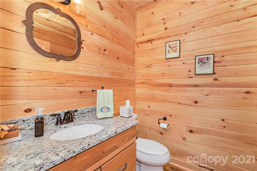 210 Angel Falls Road Clyde, NC 28721 - Photo 19 of 40 a bathroom with a granite countertop toilet sink and mirror
