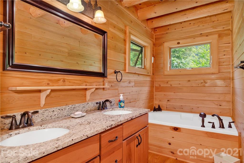 210 Angel Falls Road Clyde, NC 28721 - Photo 23 of 40 a bathroom with a granite countertop sink and a mirror
