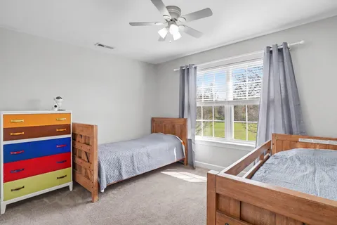 a bedroom with a bed and a dresser next to a window