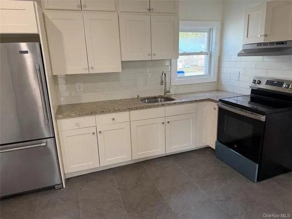 a kitchen with granite countertop white cabinets sink and stainless steel appliances