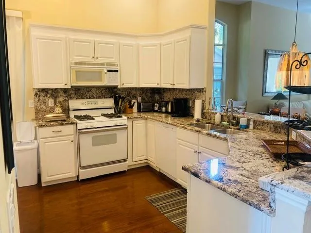 a kitchen with granite countertop a sink a stove and cabinets