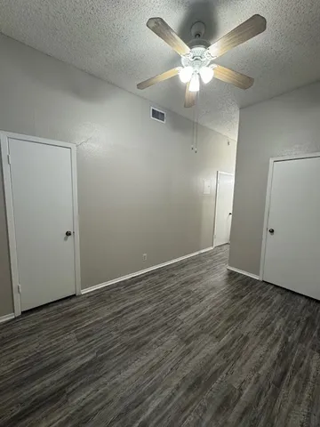 an empty room with wooden floor and fan