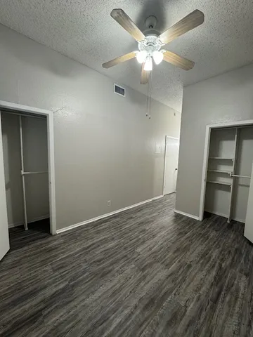 an empty room with wooden floor a ceiling fan and closet
