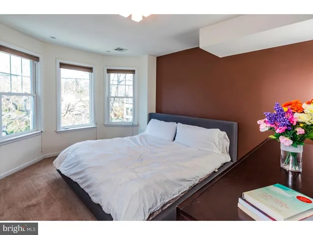 a bedroom with a bed potted plant on dresser and a window