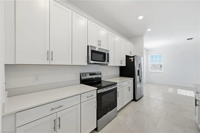 a kitchen with granite countertop white cabinets and stainless steel appliances