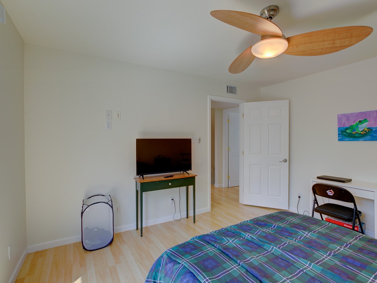710 Castle Ridge Road, Unit B Austin, TX 78746 - Photo 19 of 27 A well-lit bedroom with light wood flooring and a modern ceiling fan, offering a comfortable and functional personal space.