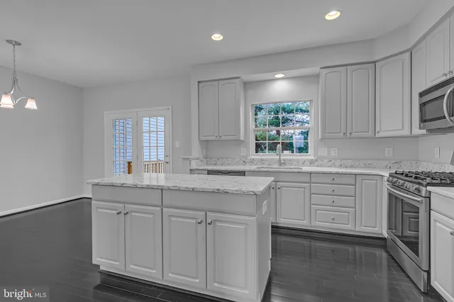 a kitchen with granite countertop white cabinets white appliances and sink